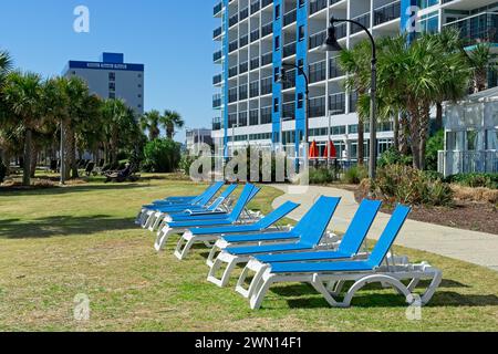 Fila di sedie a sdraio blu sul prato degli hotel alti di Myrtle Beach, South Carolina - 21 febbraio 2024 Foto Stock