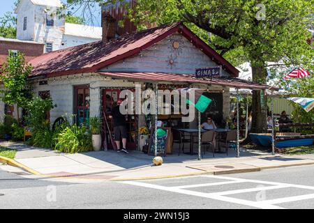 Un piccolo e intimo caffè all'aperto con clienti che si godono una giornata di sole, adornato da vivaci piante verdi e un decor rustico Foto Stock