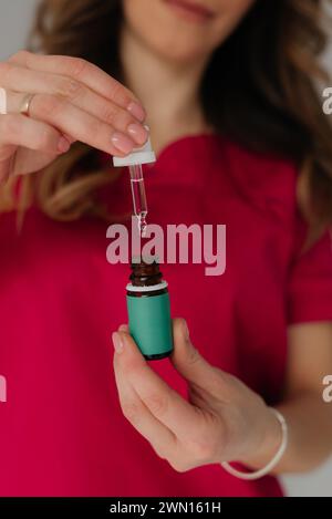 Un colpo di studio di mani di donna che gocciolano olio cosmetico Foto Stock