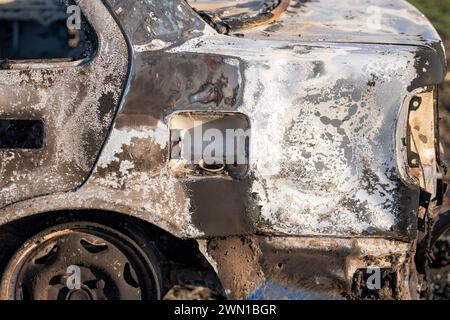 Un'auto bruciata. Macchina bruciata sul campo. Incendio dell'auto, incendio del veicolo causato da cortocircuito. Auto rubata incendio doloso intenzionale. Foto Stock