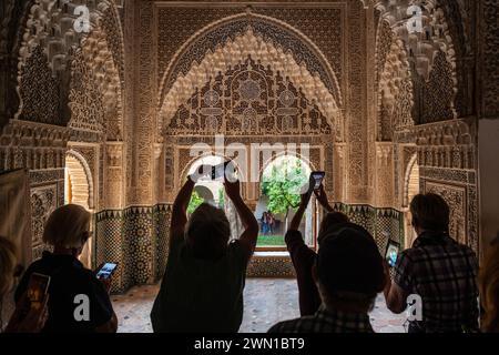 GRANADA, SPAGNA: 24 MARZO 2023: Un piccolo gruppo di turisti scatta foto con il proprio smartphone dei bassorilievi ornati degli archi e delle pareti interne Foto Stock