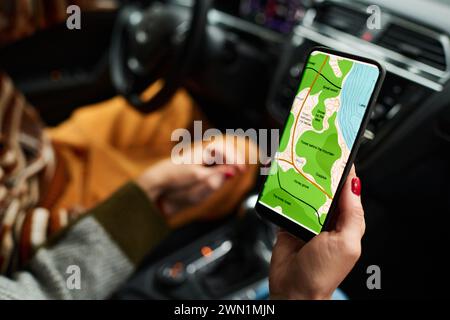 Primo piano di una donna irriconoscibile che mostra la mappa sullo schermo dello smartphone a suo marito mentre viaggia in auto Foto Stock