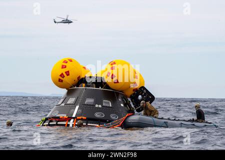 Oceano Pacifico. 25 febbraio 2024. I sommozzatori della Marina degli Stati Uniti assegnati all'Explosive Ordnance Disposal Mobile Unit 1 gonfiano una zattera di salvataggio "front Porch" della NASA durante il test di recupero in corso 11, febbraio. 25, 2024. In preparazione della missione Artemis II della NASA, che invierà quattro astronauti a Orion oltre la Luna, la NASA e il Dipartimento della difesa condurranno una serie di test per dimostrare e valutare i processi, le procedure e l'hardware utilizzati nelle operazioni di recupero per le missioni lunari con equipaggio. I moli di trasporto anfibi, come la USS San Diego, hanno capacità uniche che la rendono un'ottima soluzione Foto Stock