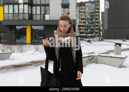 Giovane e graziosa donna con dreadlock biondi che indossa un cappotto invernale nero Foto Stock