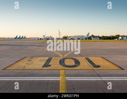 Aeroporto 101. Parcheggio per gli aerei numero 101 - segnaletica stradale dipinta sul grembiule dell'aeroporto al tramonto. Numeri neri su rettangolo giallo. Foto Stock