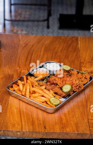 fotografia di un vassoio pieno di pollo fritto e patatine fritte con maionese e senape, scattata in diagonale Foto Stock