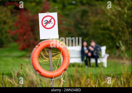 Nessun segno di nuoto e salvagente sul lago con due persone sullo sfondo sfocato Foto Stock