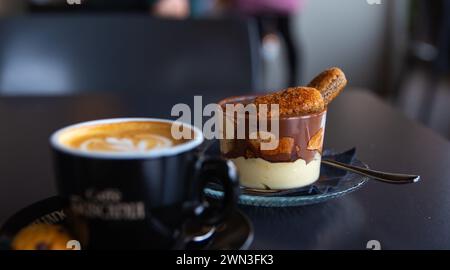 un tiramisù in una tazza di bicchiere con una tazza di caffè Foto Stock