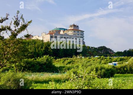 Contea di Yangyang, Corea del Sud - 30 luglio 2019: Il Sol Beach Yangyang Resort viene catturato da lontano, adagiato su vivaci campi verdi sotto un cielo blu, mo Foto Stock
