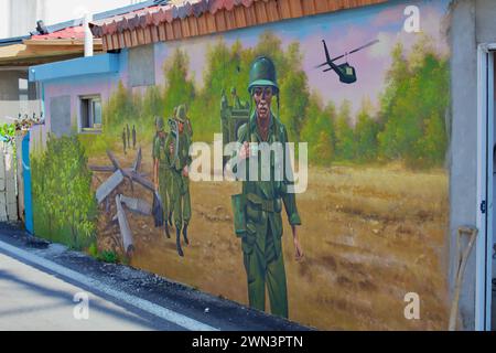 Contea di Yangyang, Corea del Sud - 30 luglio 2019: Un murale commovente su un muro basso di una casa nel porto di Gisamun raffigura soldati della guerra di Corea che camminano attraverso una foto Foto Stock