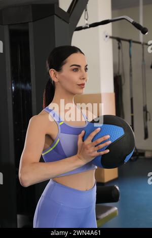 Donna sportiva con palla medica in palestra moderna Foto Stock