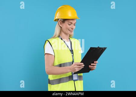 Ingegnere in elmetto che tiene appunti su sfondo azzurro Foto Stock