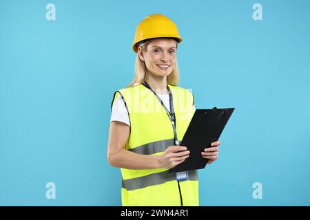 Ingegnere in elmetto che tiene appunti su sfondo azzurro Foto Stock