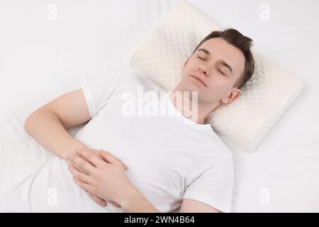 Uomo che dorme su un cuscino ortopedico nel letto Foto Stock