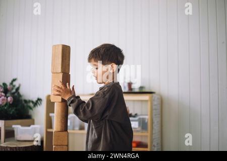 Vista laterale del bambino che si stacca i blocchi di giocattoli mentre gioca in classe all'asilo Foto Stock