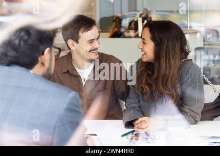 Coppia sorridente che incontra un agente immobiliare in ufficio Foto Stock