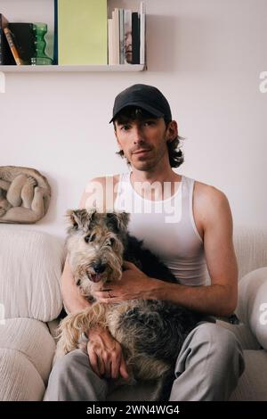 Ritratto di un uomo con un cane seduto sul divano di casa Foto Stock