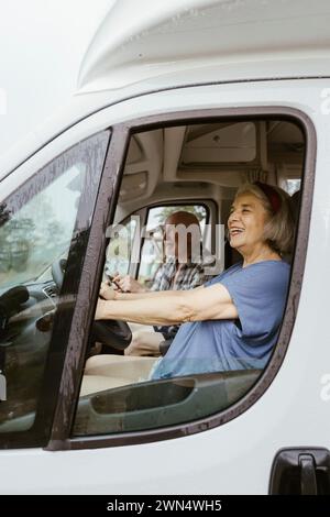 Una donna anziana felice che guida il motore a casa con un uomo durante il viaggio Foto Stock