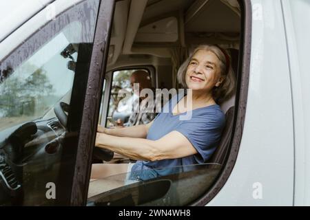 Donna anziana sorridente che guida a casa con l'uomo durante il viaggio Foto Stock