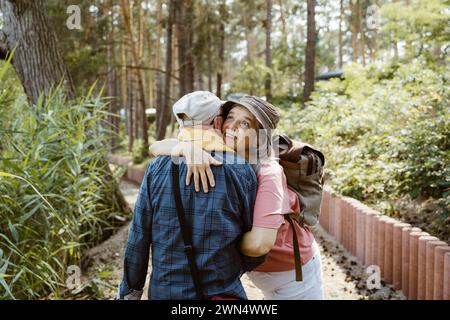 Donna anziana felice che abbraccia un uomo mentre fa escursioni nella foresta Foto Stock