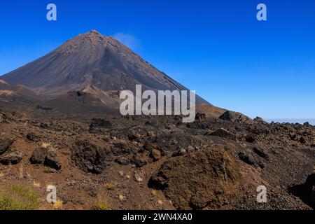 la lava rocciosa scorre di fronte all'imponente cono vulcanico classico di pico do fogo nella caldera dell'isola di fogo capo verde nelle giornate di sole Foto Stock