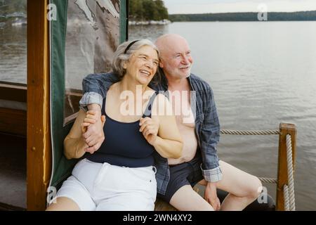 Felice coppia anziana seduta con il braccio intorno alla casa galleggiante Foto Stock