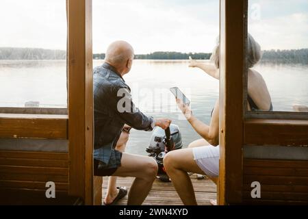 Una coppia anziana con uno smartphone seduto sulla casa galleggiante Foto Stock