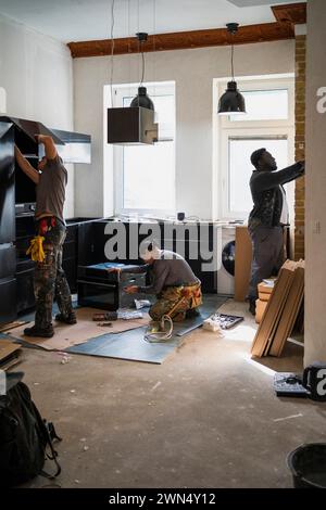 Falegnami multirazziali maschili e femminili che lavorano in cucina a casa Foto Stock