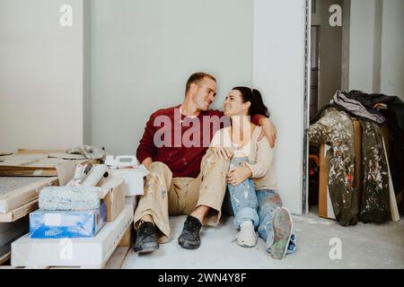 Una coppia romantica che si siede insieme in camera mentre sta ristrutturando casa Foto Stock