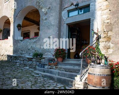 Bottiglie di alcol locale esposte su un barile di fronte a un negozio situato nella galleria di un edificio storico a Hum. Istria, Croazia 2018 Foto Stock
