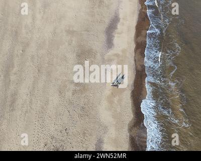 Droni a volo d'uccello dall'alto per vedere le persone che camminano sulla spiaggia, le lunghe ombre della spiaggia di Great Yarmouth Foto Stock
