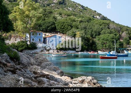 Vista dalla spiaggia di Atheras con campagna verdeggiante, mare turchese, piccole barche e graziosa villa blu. Cefalonia, Grecia. Foto Stock