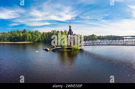 Vista dall'alto della chiesa di legno di Sant'Apostolo Andrea chiamata per la prima volta sul fiume Vuoksa con ponte. Tempio sulla piccola isola vicino al villaggio di Vasilevo Foto Stock