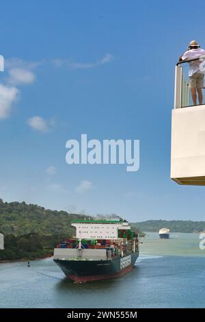 Canale di Panama, Panama - 23 gennaio 2024: Persona sul ponte superiore di una nave da crociera che guarda una nave container di passaggio Foto Stock