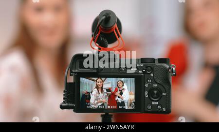 La telecamera retrovisiva mostra lo schermo di due donne influencer che girano video vlog recensisci abiti prim social media o blog. Ragazze con studio di abbigliamento Foto Stock