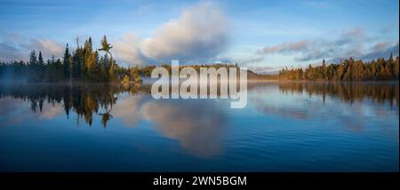 Panorama del lago blu nel nord del Minnesota con un'isola e pini in una nebbiosa mattina di settembre Foto Stock