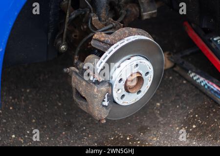 Una ruota viene rimossa da un'auto blu in primo piano Foto Stock