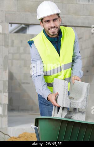 muratore che mette blocchi sul cilindretto Foto Stock