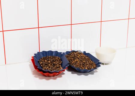 Assaggi di caffè arabica tostato sono contenuti in vassoi di plastica su una scrivania bianca Foto Stock