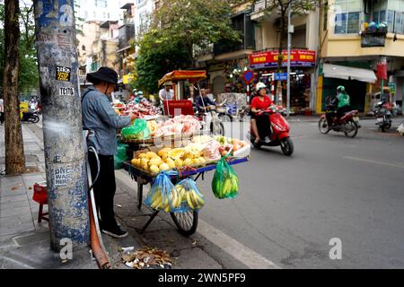 Strade molto trafficate nella città vecchia di Hanoi, con biciclette e venditori di cibo Foto Stock