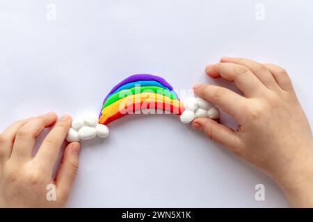 Il bambino scolpisce un arcobaleno e nuvole di plastilina. Creatività dei bambini. Foto Stock