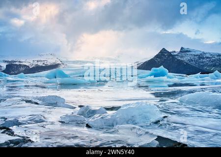 Un lago glaciale islandese con ormeggi di ghiaccio distaccati che galleggiano nelle acque gelide del lago. Foto Stock