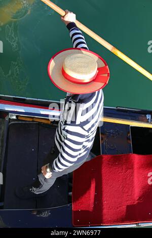 Gondoliere con un cappello che canta una gondola in un canale di Venezia fotografato dall'alto Foto Stock