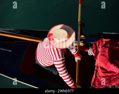 Gondoliere con un cappello che canta una gondola in un canale di Venezia fotografato dall'alto Foto Stock