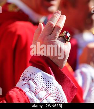 mano del sacerdote con un anello con un grande rubino rosso mentre dà la benedizione ai fedeli durante il rito religioso Foto Stock