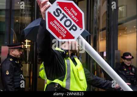 Londra, Regno Unito. 29 febbraio 2024. Gli agenti di polizia della città di Londra spostano un finto checkpoint israeliano eretto da attivisti per il clima e i diritti umani fuori dagli uffici di AXA UK plc durante una protesta contro gli investimenti dell'assicuratore in società legate all'occupazione illegale dei territori palestinesi. La protesta è stata organizzata da gruppi tra cui Extinction Rebellion, War on Want, Global Justice Now, Climate Justice Coalition e Green New Deal Rising come parte di una settimana di azioni mirate all'industria assicurativa per il suo ruolo nell'emergenza climatica ed ecologica. Crediti: Mark Kerrison/Alamy Live Foto Stock