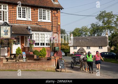 Villaggio di Minstead vicino a Lyndhurst, due donne con carrozza trainata da cavalli fuori dal fidato Servant Inn, Hampshire, Inghilterra, Regno Unito, 2023 Foto Stock