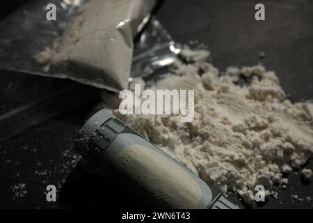 Tossicodipendenza. Cocaina e banconota da un dollaro arrotolato su tavola grigia, primo piano Foto Stock