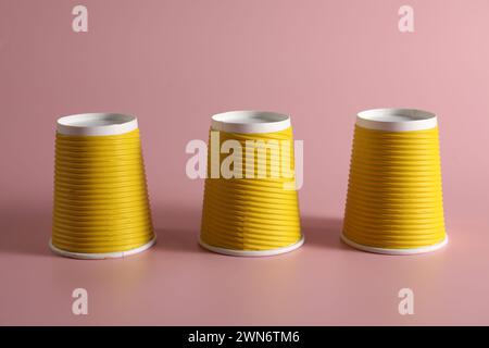 Gioco di shell. Tre tazze gialle su sfondo rosa Foto Stock