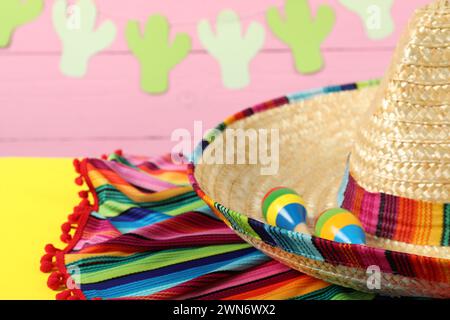 Cappello sombrero messicano, poncho e maracas su tavola gialla, primo piano. Spazio per il testo Foto Stock